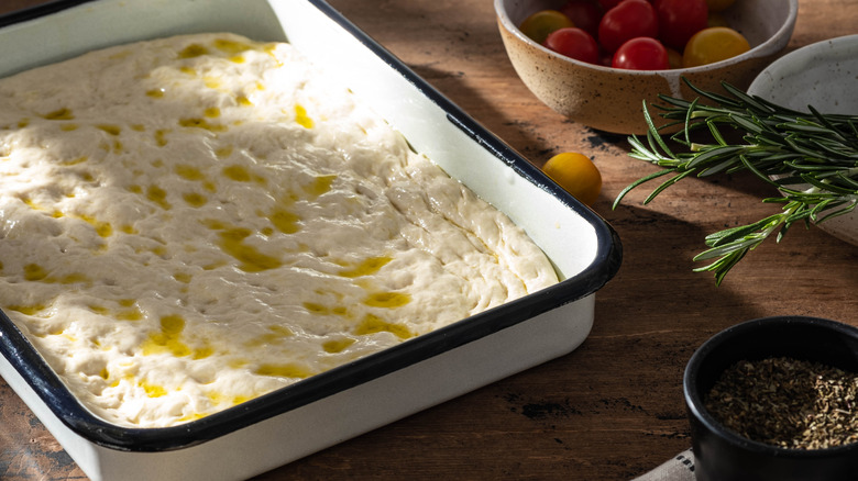 focaccia dough in tin with olive oil left to rise