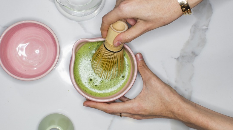 Hands whisking matcha