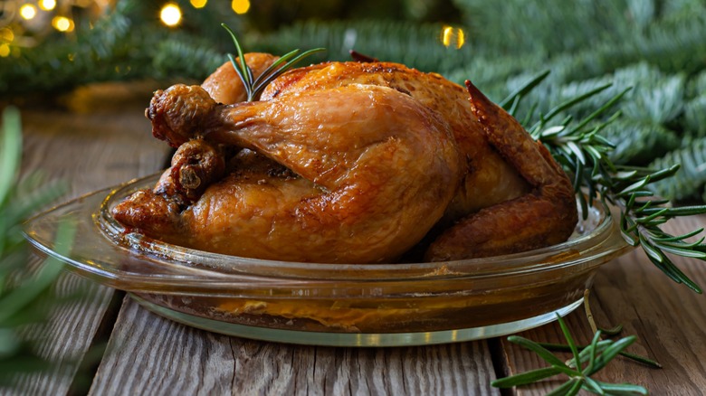 A roasted and garnished turkey on a glass dish