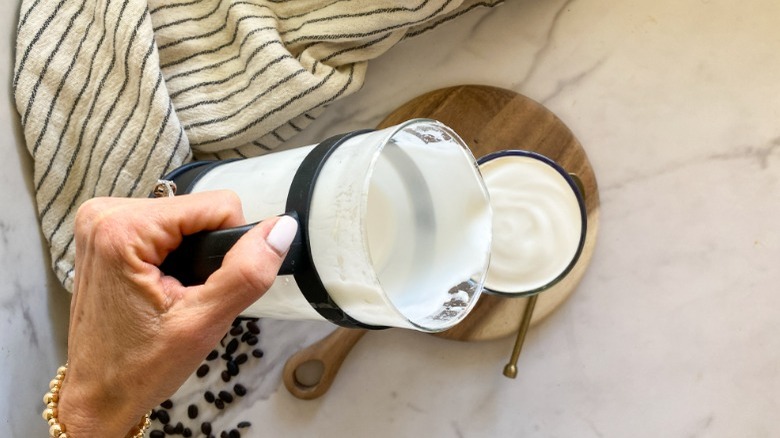 pouring frothy milk to mug