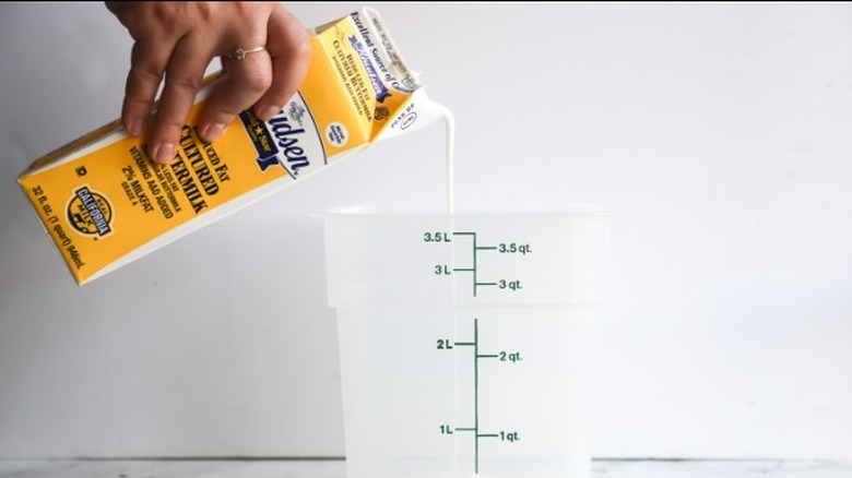 hand pouring buttermilk into container