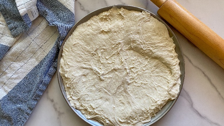 dough on pan with rolling pin