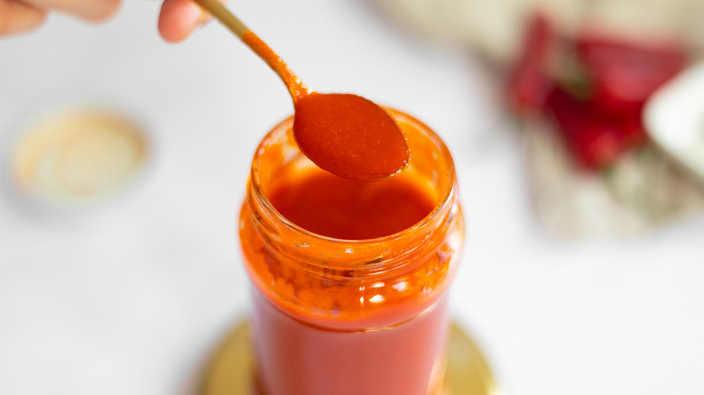 spoon with sriracha and jar