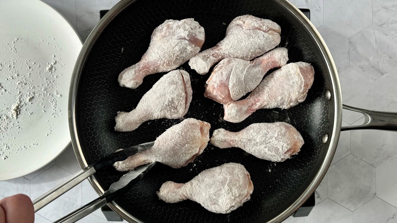 floured chicken legs in pan