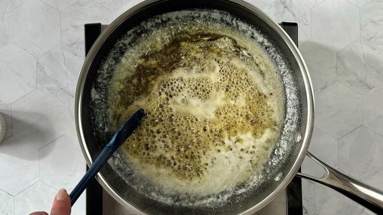 hand stirring sauce in pan