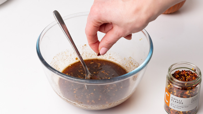 adding chili flakes to bowl