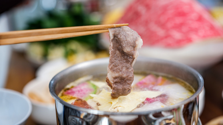 Chopsticks cooking beef in Chinese hot pot