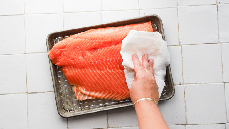 Patting salmon dry with towel