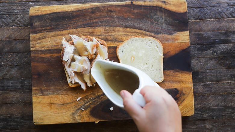 Pouring gravy on turkey sandwich