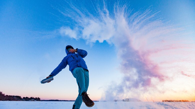 Person throwing hot water in a frozen landscape