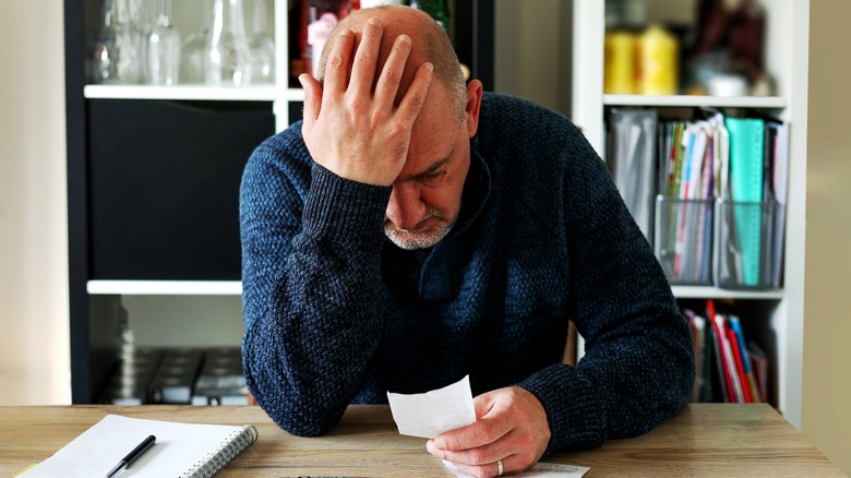 Upset man looks at receipt