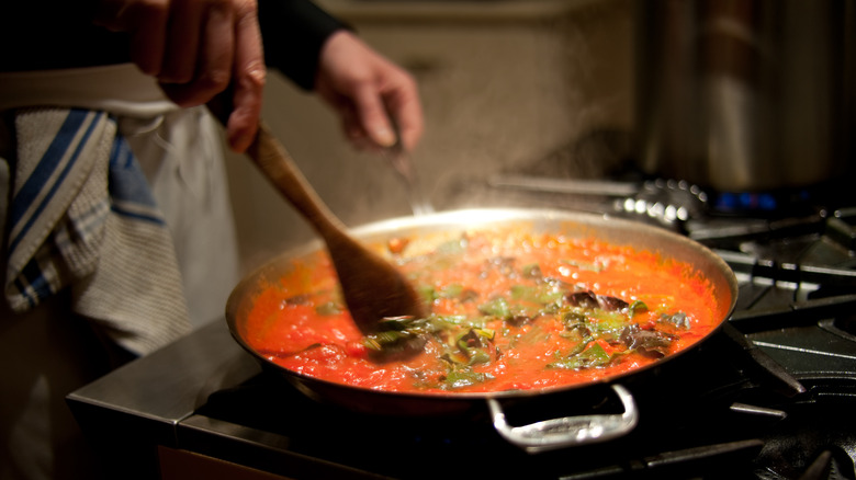 Hand stirring sauce in a pot