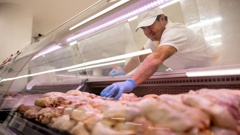 butcher grabbing raw chicken