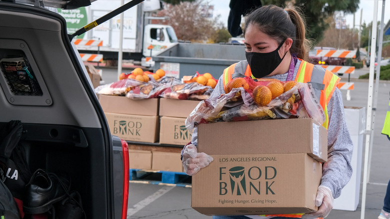 Food bank employee loads box into a car