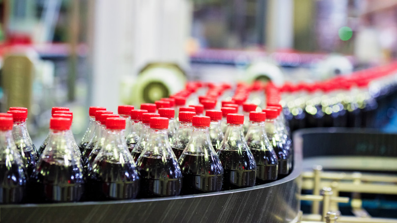 unlabeled coca-cola bottles on factory conveyor belt