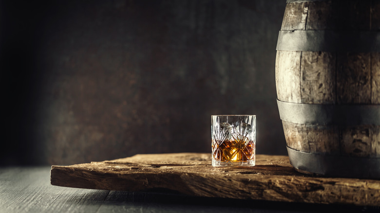 Glass of bourbon next to barrel