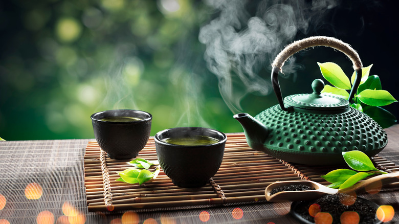A kettle with green tea and two cups