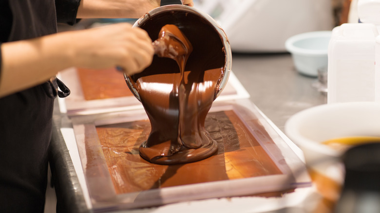 Confectioner pouring chocolate into tray
