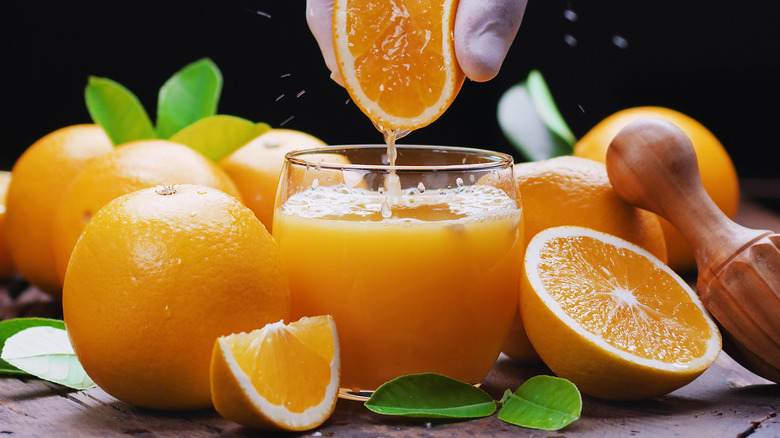 Hand squeezing orange juice into glass