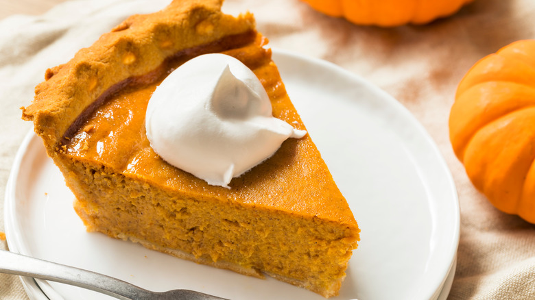 Pumpkin pie with whipped cream on top with a fork