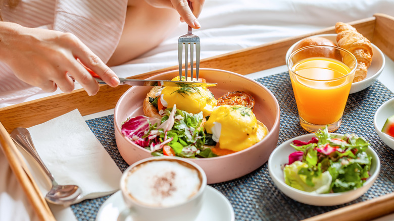 Woman cutting eggs benedict with a fork and knife