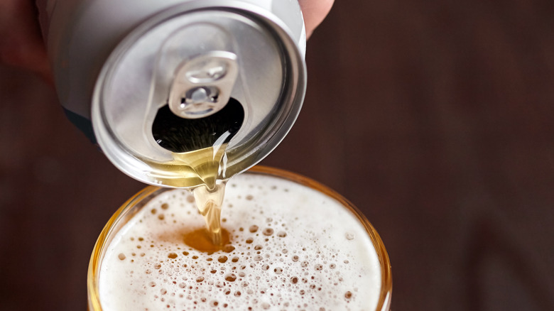 canned beer is poured into a glass