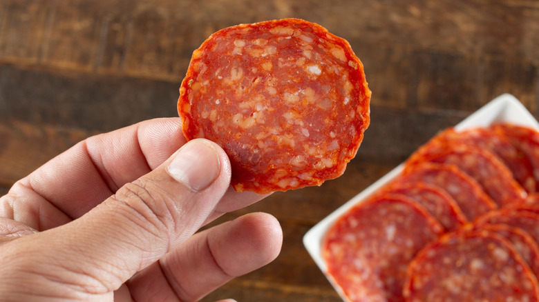 hand holding up a slice of pepperoni