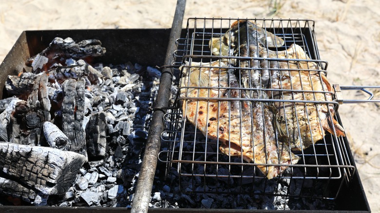 whole carp in a grill basket over coals