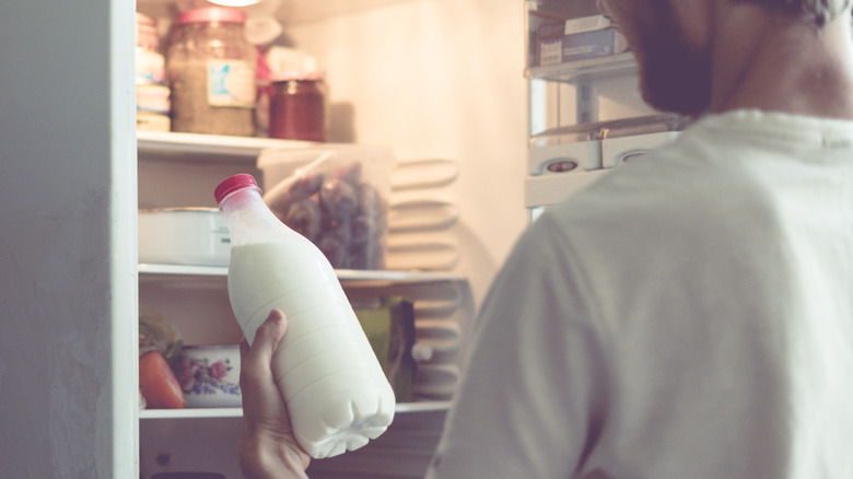 man inspecting milk bottle