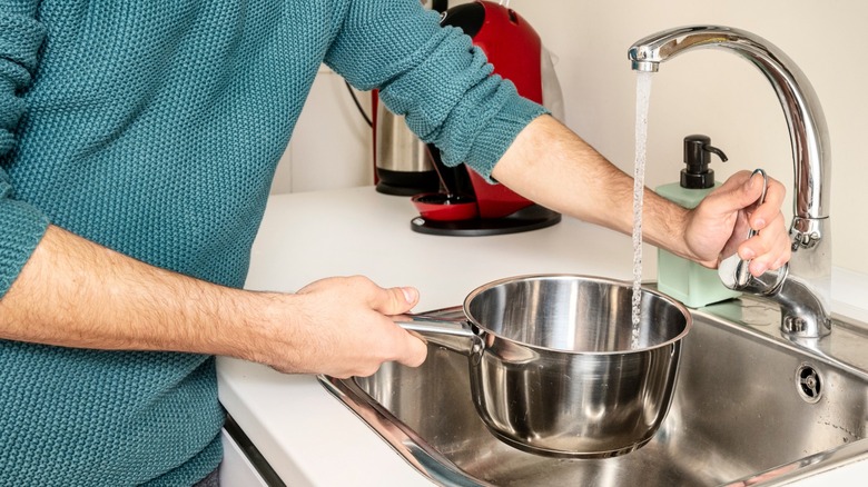 Hands filling pot with water at faucet