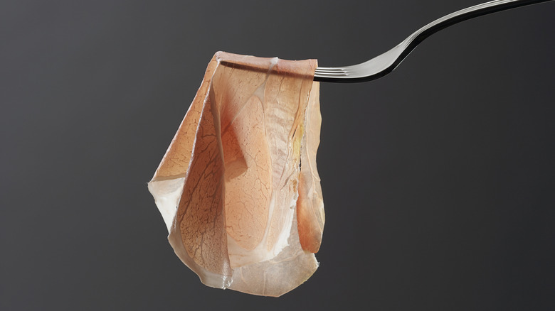Prosciutto hanging from fork