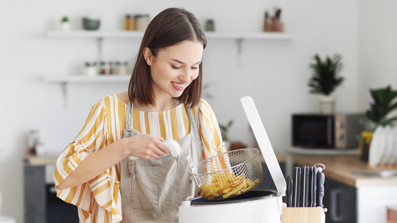 woman taking fries from fryer