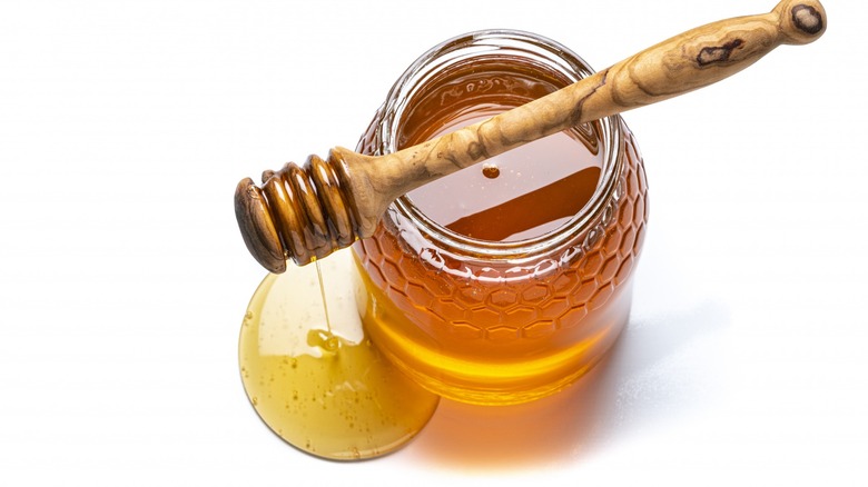 Open honey jar with honey dipper