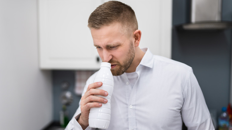 man smelling drink in bottle