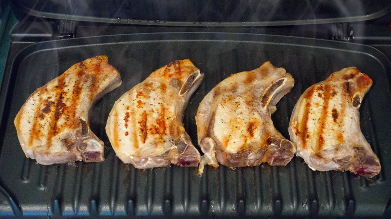 four pork chops on a grill