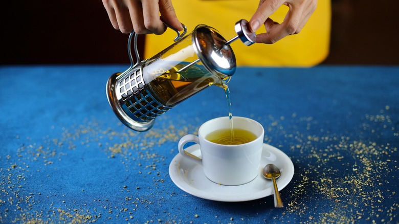 Person pouring tea from a French press