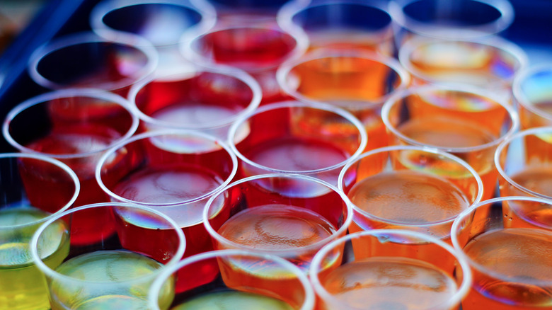 A tray full of different colors of Jell-O shots in small plastic cups