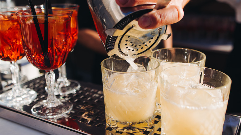 Bartender pouring cocktails from a shaker into a glass