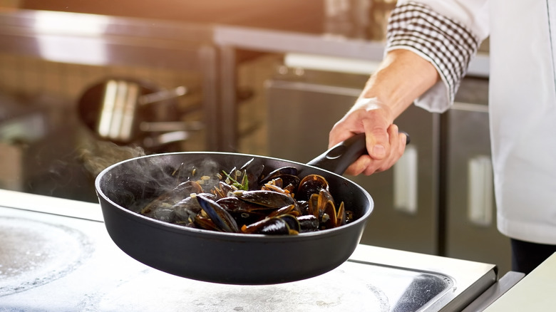 chef frying mussels in pan