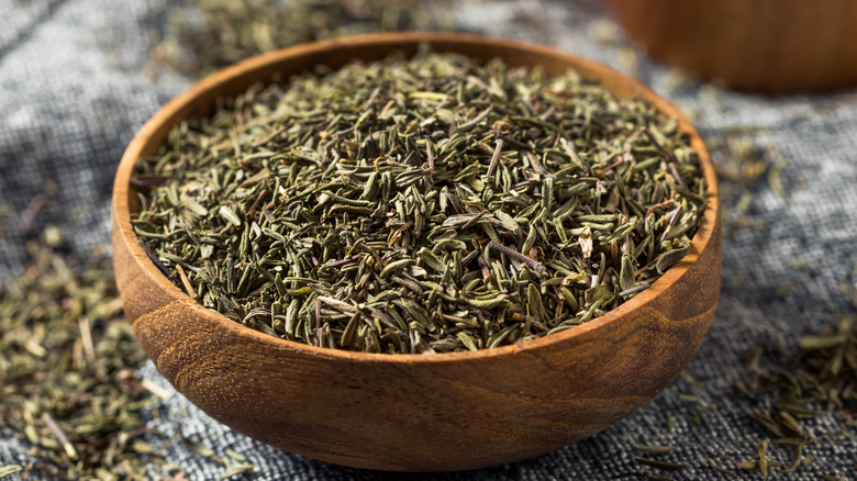 Dried thyme leaves in wooden bowl