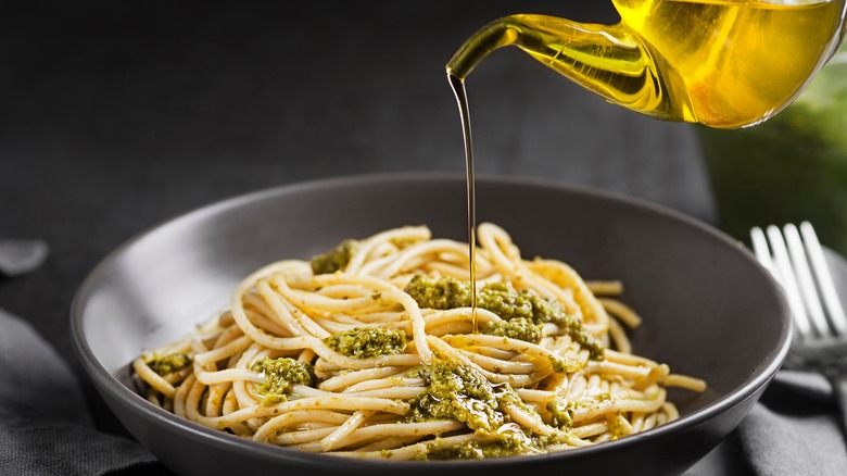 drizzling oil on pasta dish