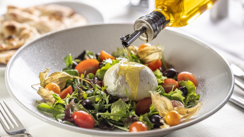 drizzling olive oil on burrata salad