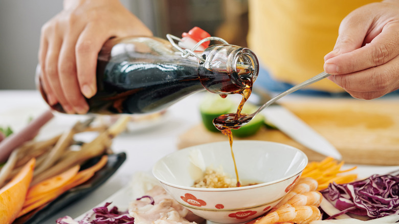 Woman pouring soy sauce into bowl