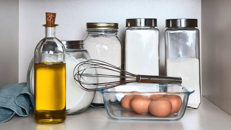 jars of flour near bottle of oil and dish with eggs