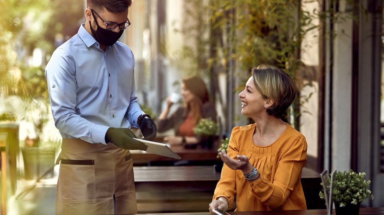 Server handing a menu to a smiling customer