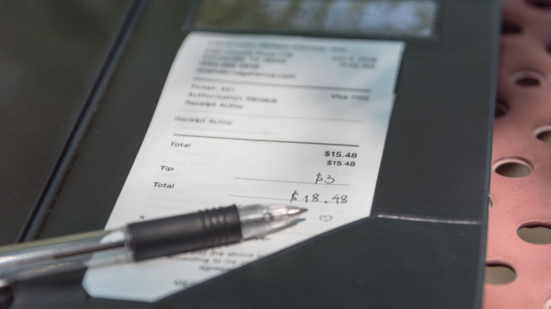 A check in a check presenter with a gratuity or tip written in