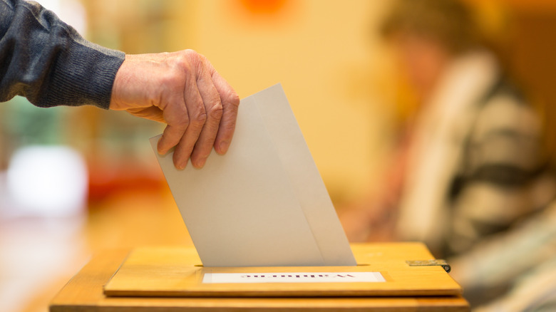 hand placing ballot into box