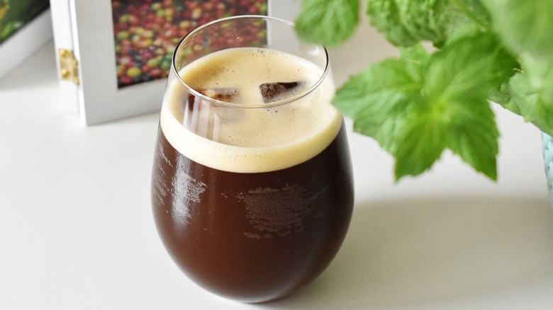 Glass of nitro cold brew with plant and book