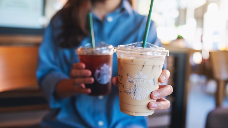 A starbucks customer holding two drinks