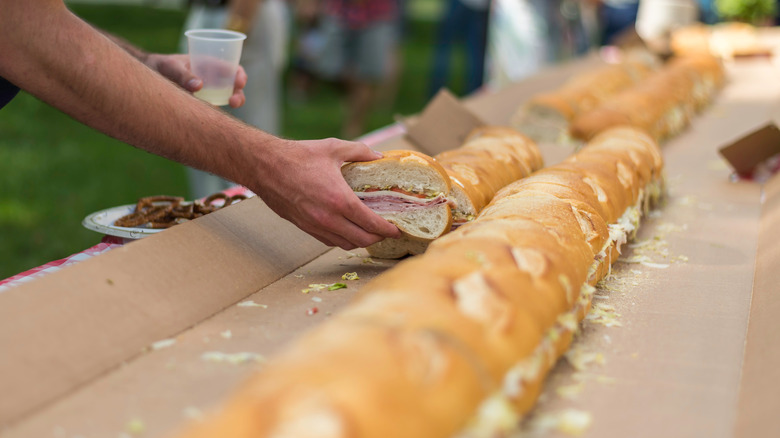 Hand lifting piece of huge hero sandwich